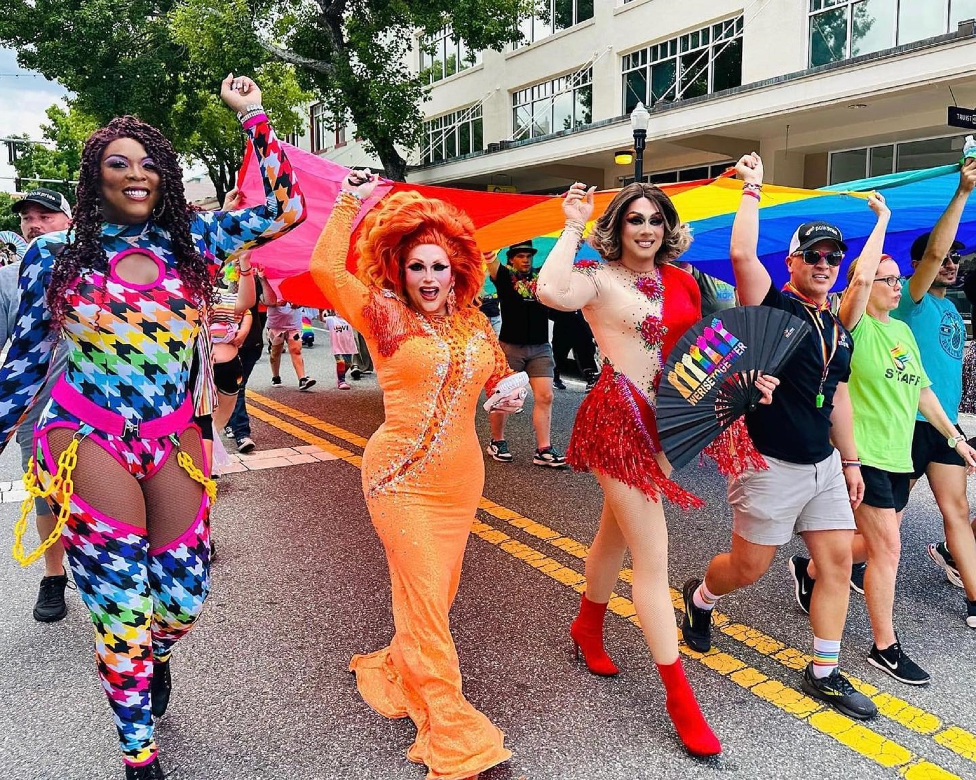 Pride in the Park 2024 attendees carry the Pride flag around Munn Park.